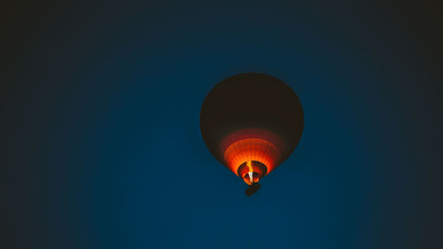 Low angle view of hot air balloon flying against clear blue sky at dusk