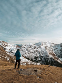 Rear view of man standing on mountain against sky