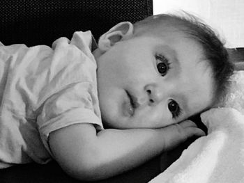 Portrait of baby girl lying on bed at home