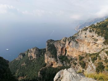 Scenic view of rocks by sea against sky