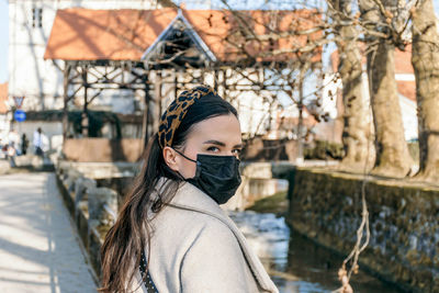 Beautiful young woman wearing black face mask, looking at camera. epidemic, covid, corona virus.