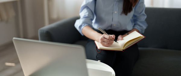 Midsection of man using laptop while sitting on table