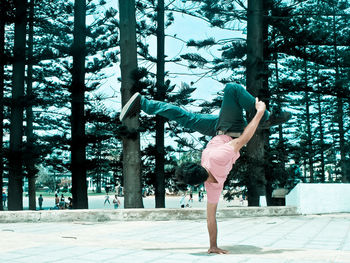 Full length of young woman dancing against trees