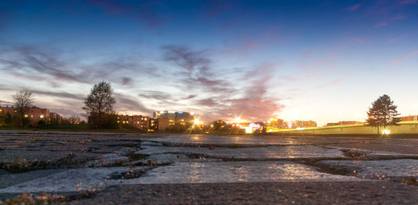 Surface level of snowy field against sky during sunset