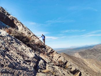 Low angle view of person on rock against sky