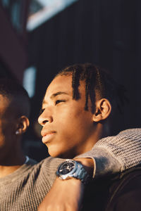 Thoughtful teenage boy looking away by friend in city