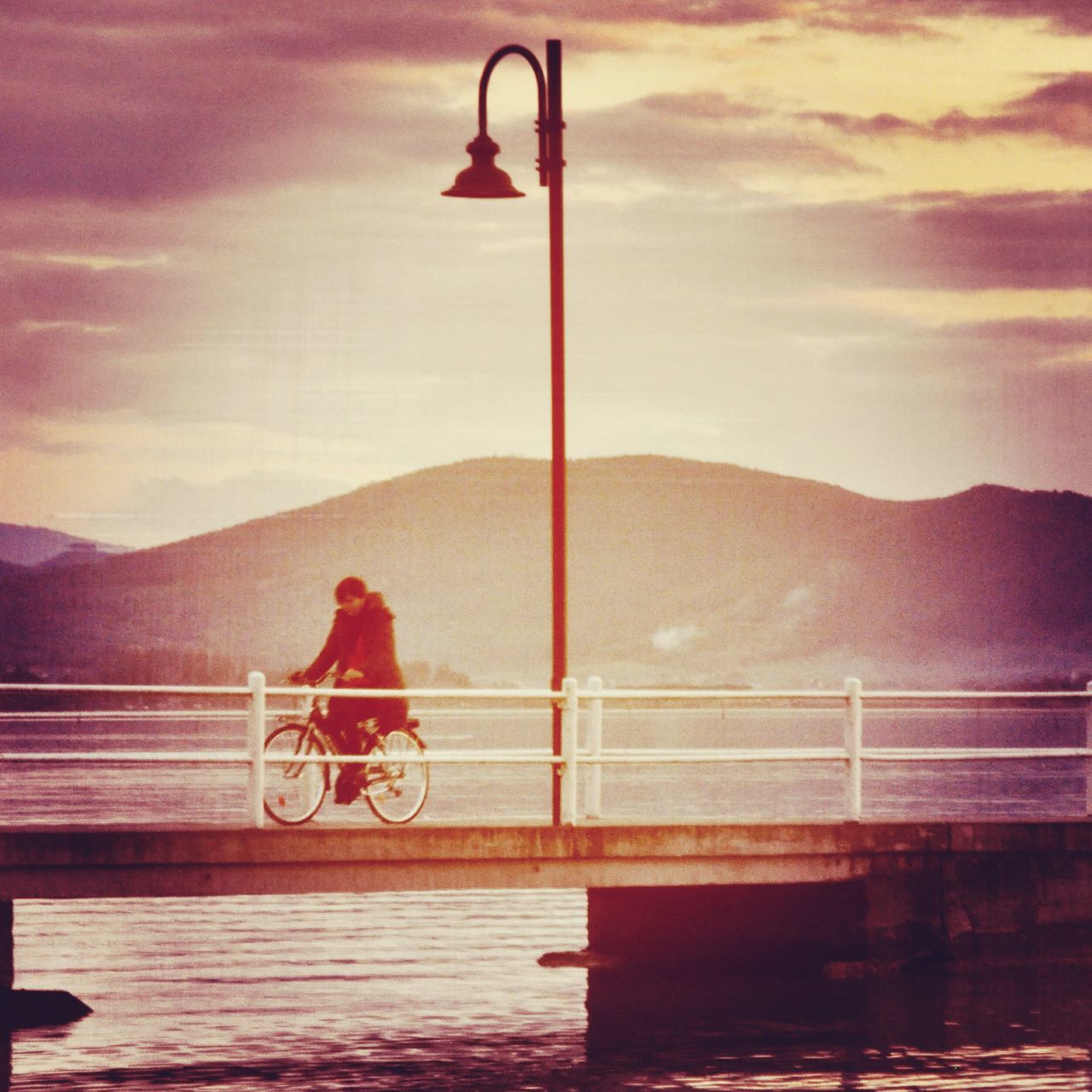 MAN CYCLING ON BICYCLE AGAINST MOUNTAIN