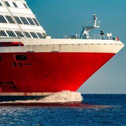 Red ship sailing in sea against clear sky