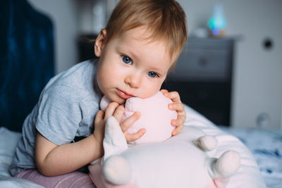 Little child is having fun, playing with soft toys on the couch at home.