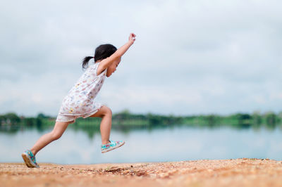 Girl running on field by river