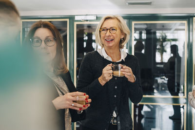 Colleagues having tea while standing in office