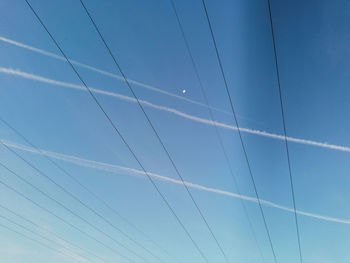 Low angle view of vapor trails against clear blue sky