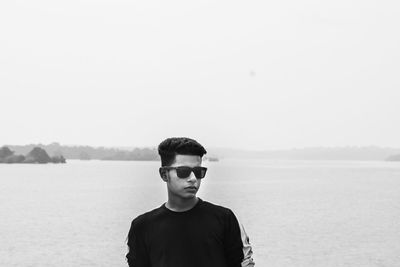 Portrait of young man standing against sea