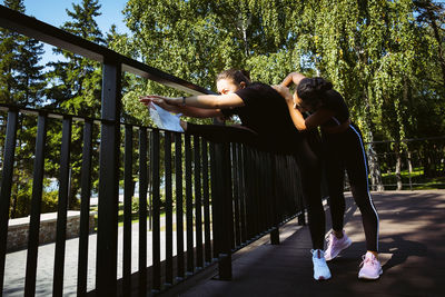 Girl in sportswear on a sunny summer day on the embankment in the park doing fitness and stretching