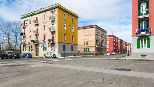 Road by buildings against sky in city