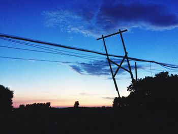 Low angle view of electricity pylon against cloudy sky