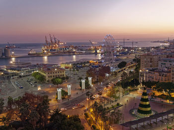 High angle view of illuminated cityscape against sky at sunset