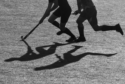 Low section of players playing hockey on field