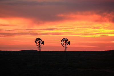 Scenic view of silhouette field against orange sky