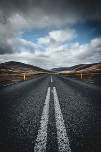 Surface level of country road against cloudy sky