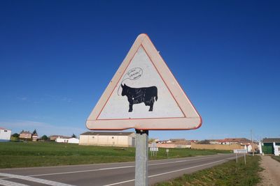 Animal crossing sign by road against clear sky