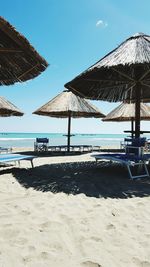 Beach umbrellas and lounge chairs against sky