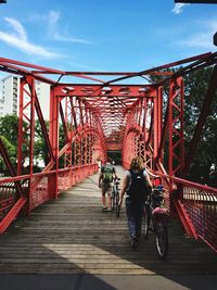 Rear view of people on footbridge against suspension bridge