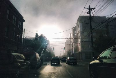 Cars on street in city against sky