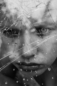 Close-up portrait of woman seen through broken glass