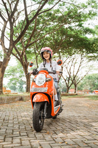 Side view of man riding motor scooter on road