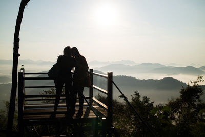 Silhouette friends standing on observation point against sky