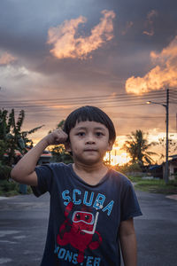 Portrait of boy standing against sky during sunset