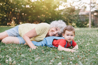 Portrait of happy friends sitting on grass against plants