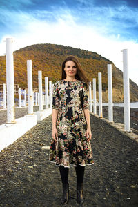 Portrait of young woman standing against building