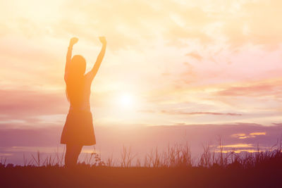 Silhouette woman standing on field against sky during sunset