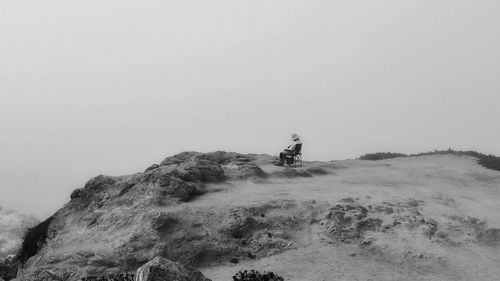 People on rock against clear sky
