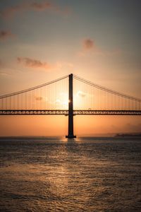 Bridge over sea against sky during sunset