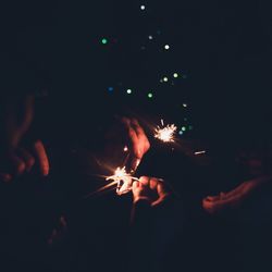 Close-up of hand holding illuminated firework display at night