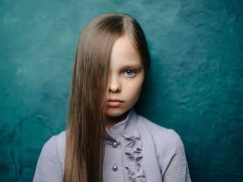 Portrait of girl standing against blue wall