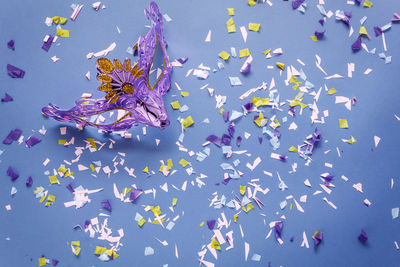 Close-up of venetian mask and confetti over blue background
