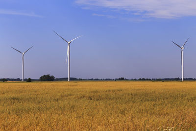 Wind turbines on field against sky