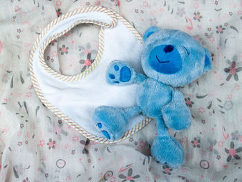 High angle view of baby bib and stuffed toy on fabric