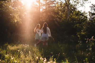 Two happy girlfriends walking in forest during summer