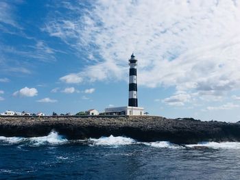 Lighthouse by sea against sky