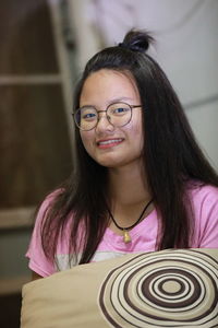 Portrait of smiling teenage girl wearing eyeglasses at home