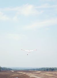 Airplane flying over land against sky