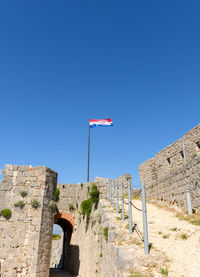 Low angle view of croatian flag on pole at klis fortress near split, croatia