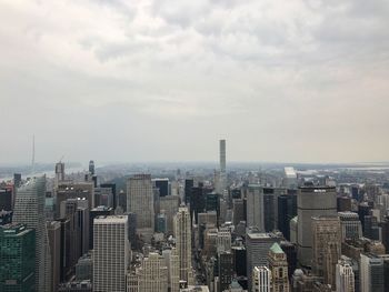 Aerial view of city buildings against cloudy sky