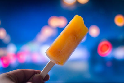 Close-up of hand holding popsicle at night