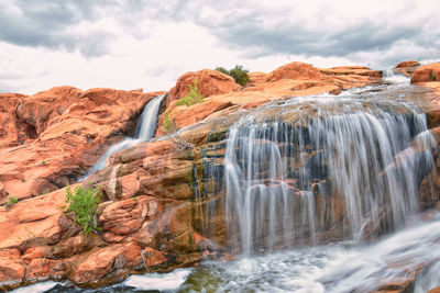 Scenic view of waterfall against sky